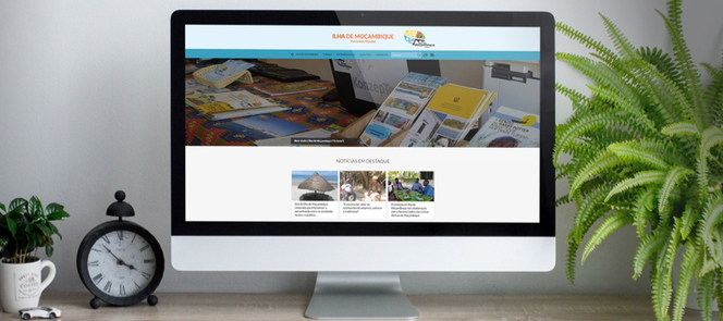 fundo de uma secretaria com um ecran de computador a apresentar o site da ilha de mocambique